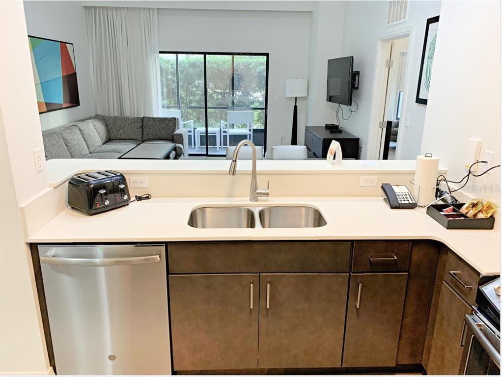 A kitchen sink and dishwasher overlook a living area with a sofa and patio door — 14501 GROVE RESORT AVENUE UNIT 3109, WINTER GARDEN, FL