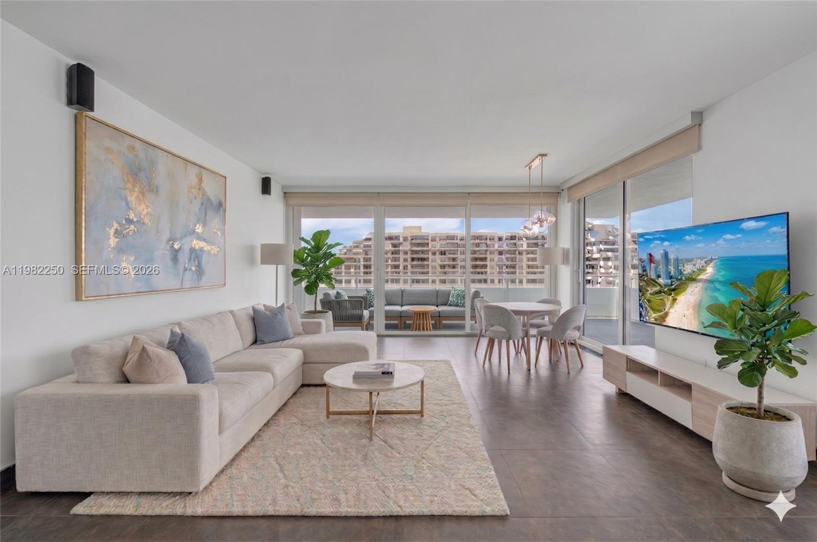 A modern living and dining room features a sectional sofa, television, and balcony access — 199 Ocean Lane Dr # 1009, Key Biscayne FL 33149, KEY BISCAYNE, FL