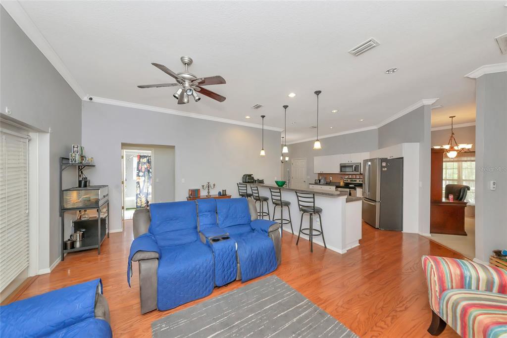 An open-concept living room and kitchen featuring hardwood floors, a blue sofa, and bar seating — 11851 69TH STREET E, PARRISH, FL