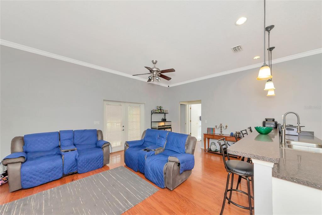 A living room with two blue-covered recliners, hardwood floors, and an adjacent kitchen island — 11851 69TH STREET E, PARRISH, FL