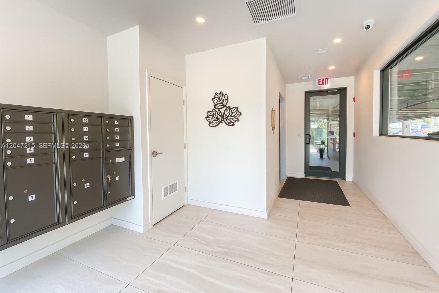 A bright lobby features a wall of metal mailboxes, tile flooring, and a glass exit door — 1950 Fletcher St # 305, Hollywood FL 33020, HOLLYWOOD, FL