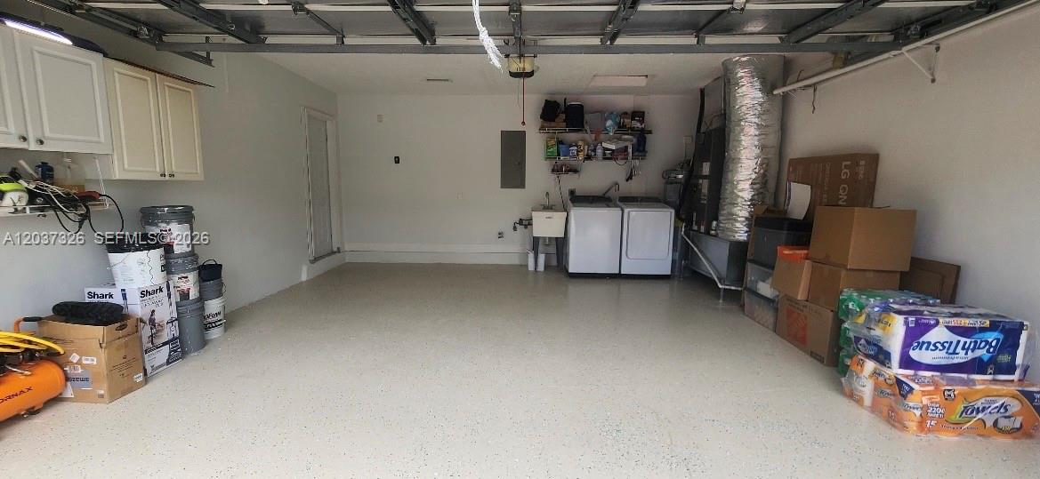 A garage with a concrete floor, laundry appliances, storage shelves, and various household items — 649 Willow Bend Rd, Weston FL 33327, WESTON, FL