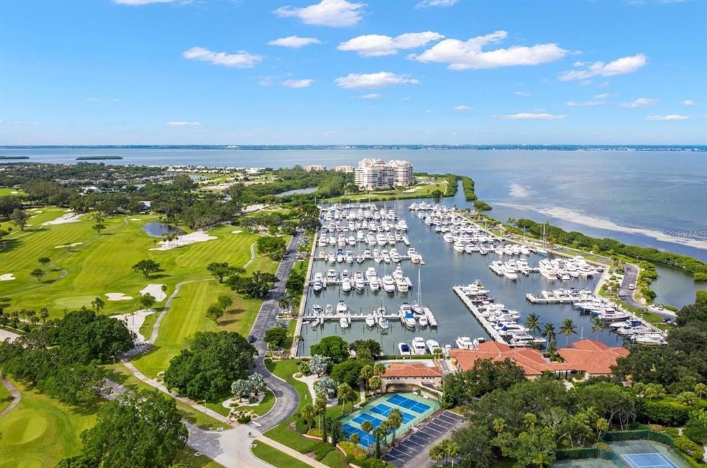 An aerial view shows a marina with many boats, a golf course, and tennis courts — 2600 HARBOURSIDE DRIVE UNIT L-11, LONGBOAT KEY, FL