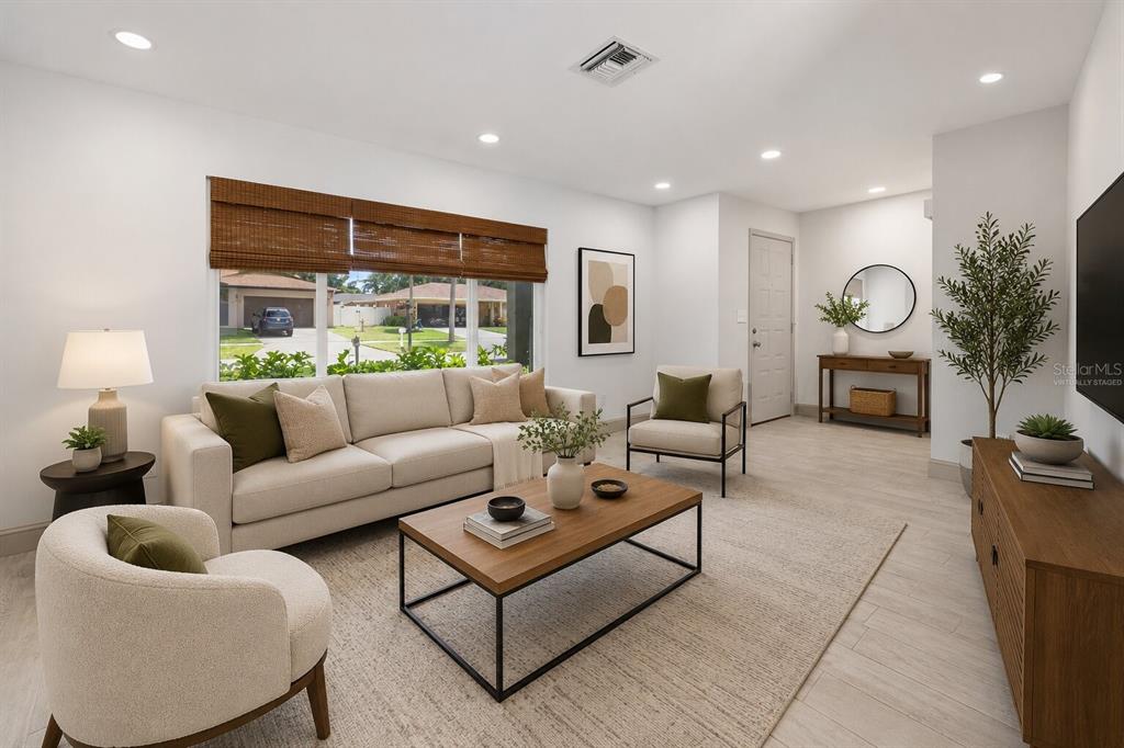 A living room features a beige sofa, two armchairs, a coffee table, and wood flooring — 2778 BRATTLE LANE, CLEARWATER, FL