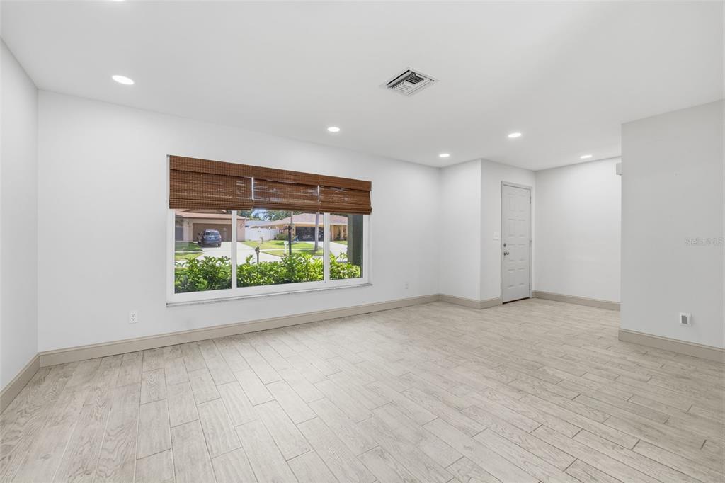 An empty room with white walls, recessed lighting, and light-colored wood-look tile flooring — 2778 BRATTLE LANE, CLEARWATER, FL