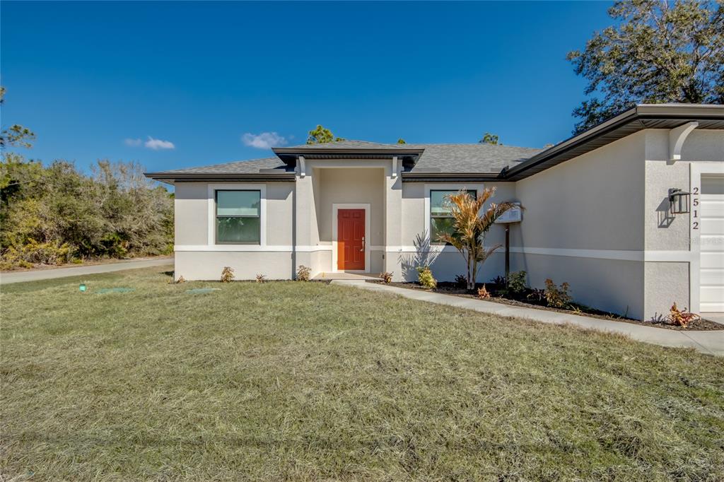 A single-story house with a light-colored stucco exterior and a bright orange front door — 2512 48TH STREET W, LEHIGH ACRES, FL
