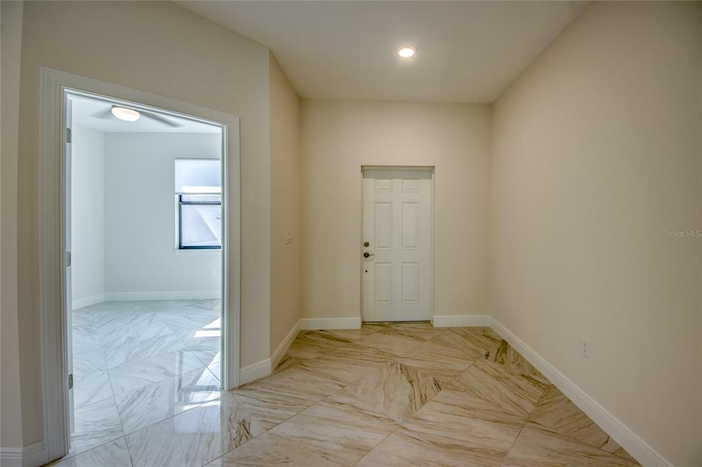 A tiled entryway leads to a doorway opening into a room with matching tile flooring — 2512 48TH STREET W, LEHIGH ACRES, FL