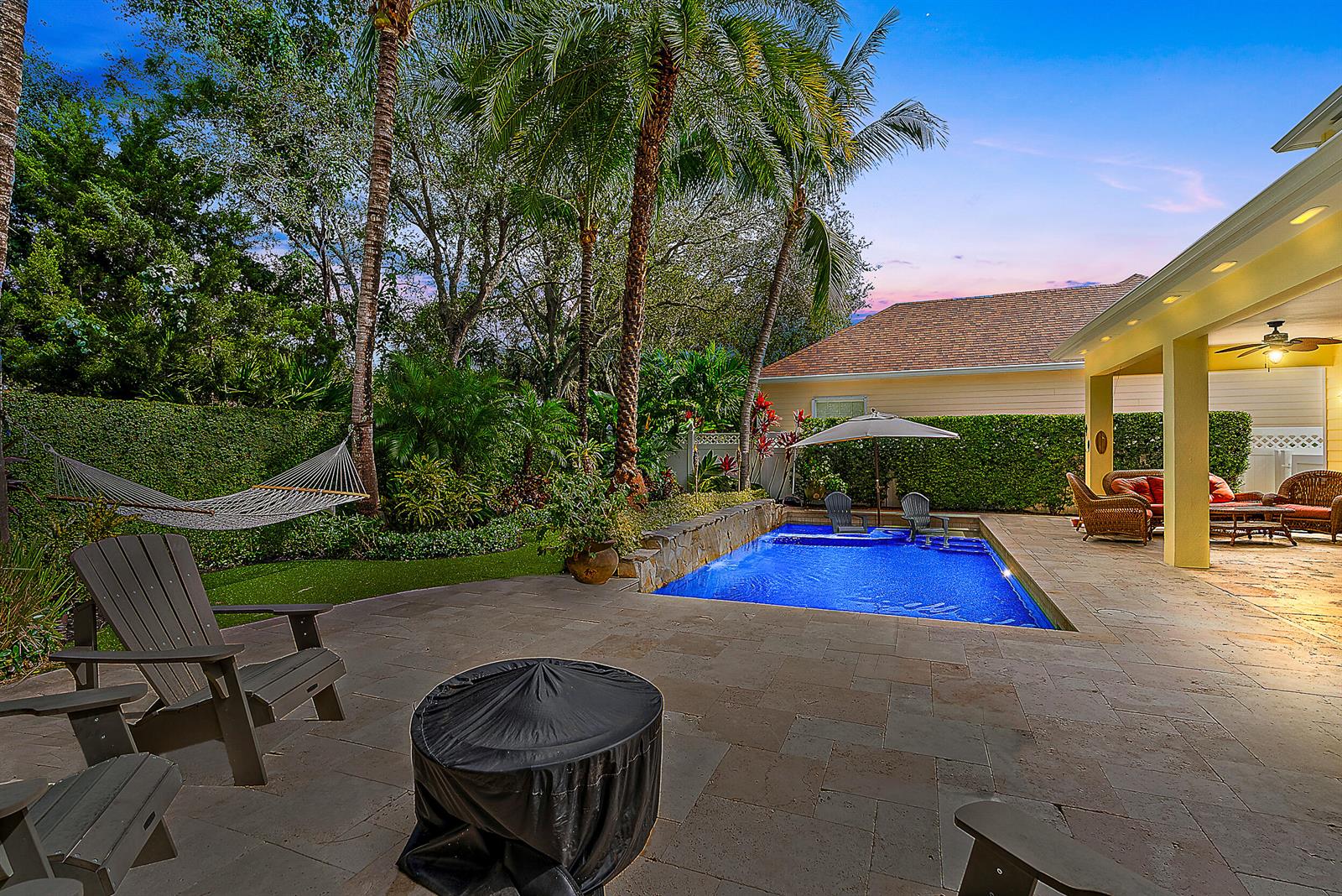 A backyard patio features a swimming pool, a fire pit, a hammock, and covered seating — 140 Sweet Bay Circle, Jupiter FL 33458, JUPITER, FL