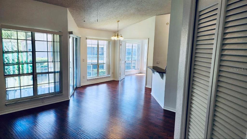 A living area with dark wood floors, large windows, and a vaulted ceiling — 4623 GATE PLACE UNIT 206, ORLANDO, FL