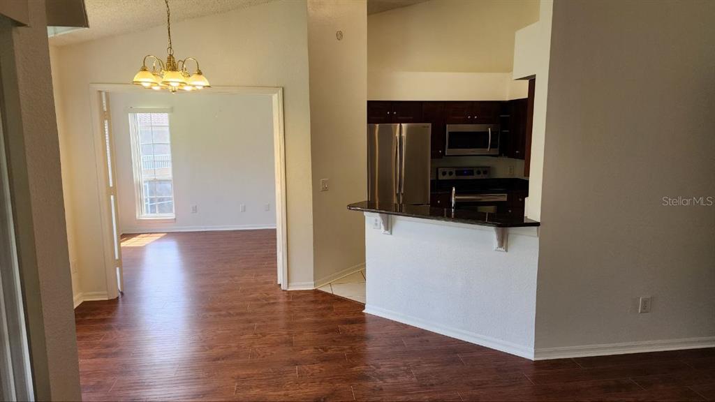 A kitchen with stainless steel appliances and a breakfast bar overlooks a dining area — 4623 GATE PLACE UNIT 206, ORLANDO, FL