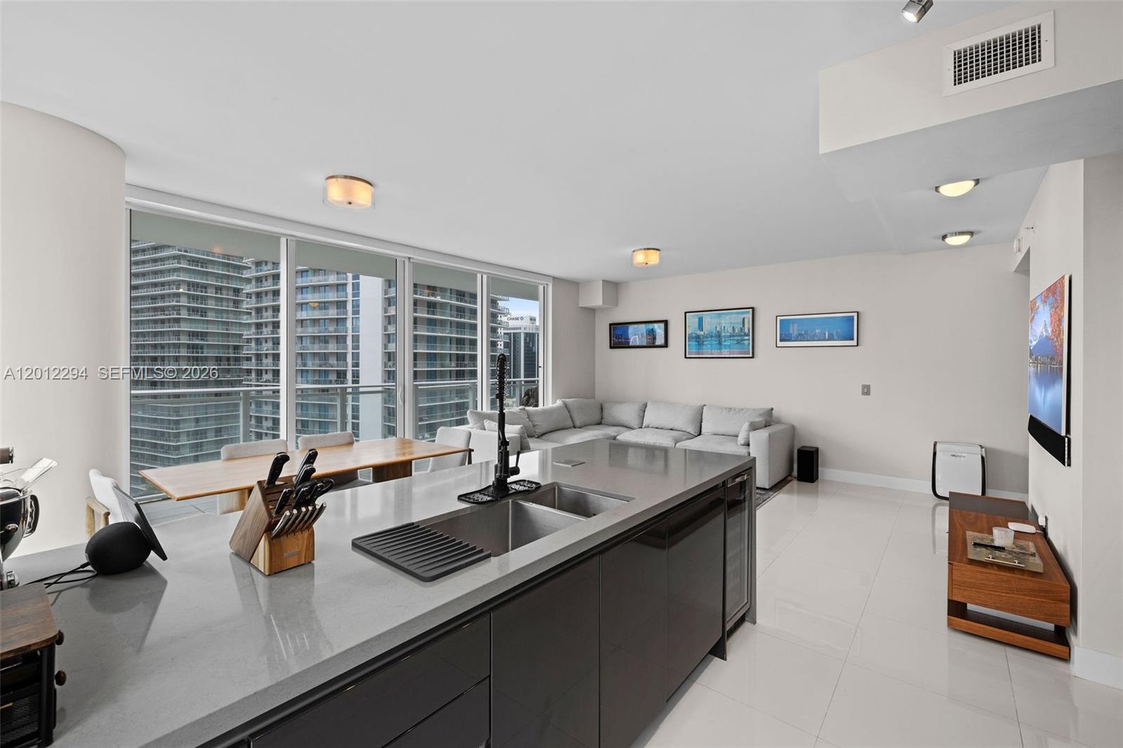 A modern kitchen island with a sink overlooks a living area with floor-to-ceiling windows — 1080 Brickell Ave # 2001, Miami FL 33131, MIAMI, FL