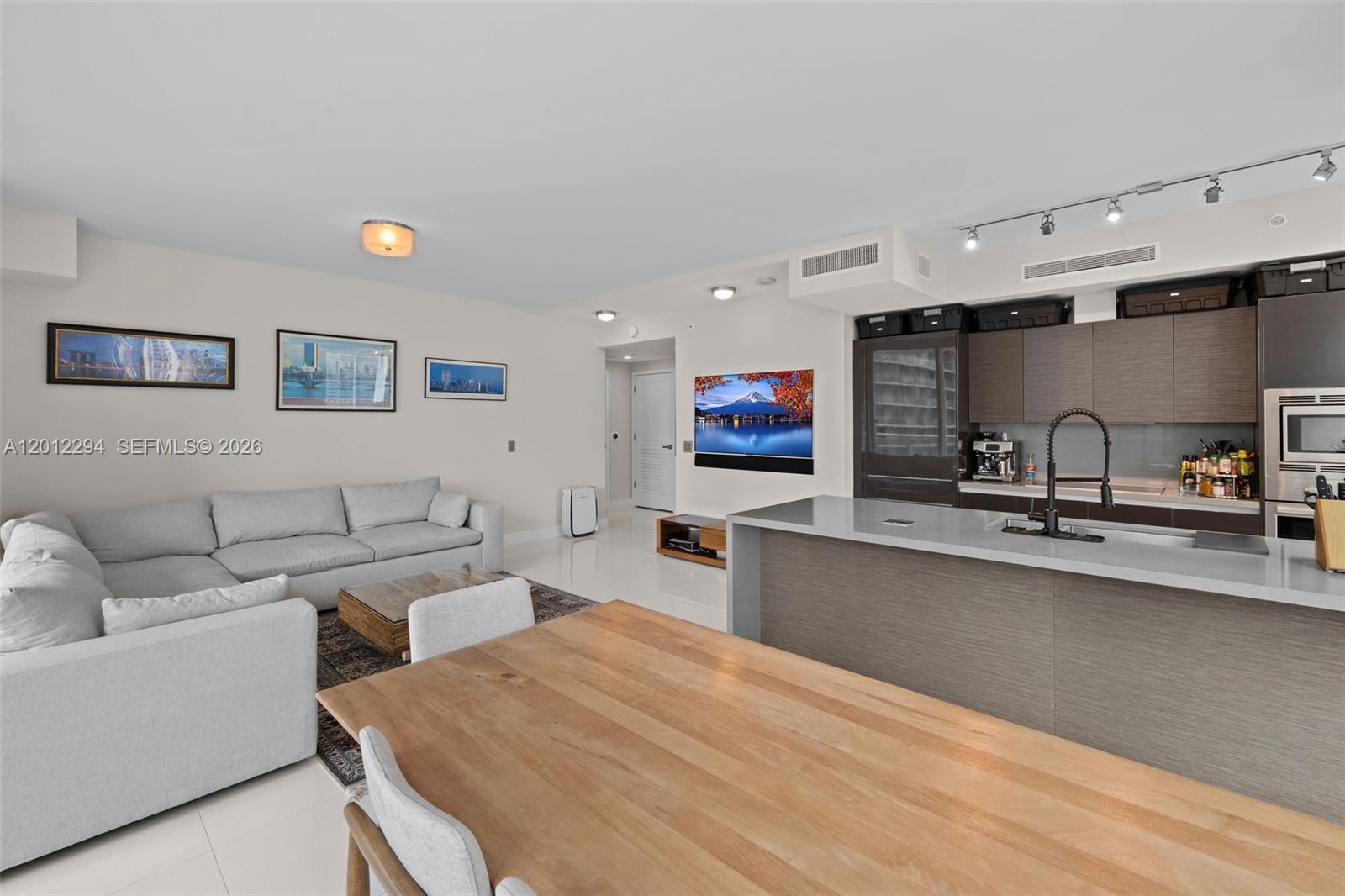 An open-concept living area features a kitchen island, dining table, and a sectional sofa — 1080 Brickell Ave # 2001, Miami FL 33131, MIAMI, FL