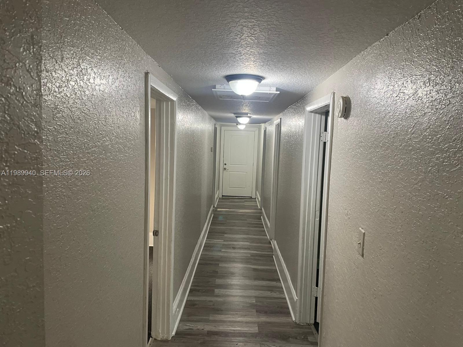 A narrow hallway features gray wood-look flooring, textured walls, and two ceiling light fixtures — 1129 Grothe St, Jacksonville FL 32209, JACKSONVILLE, FL
