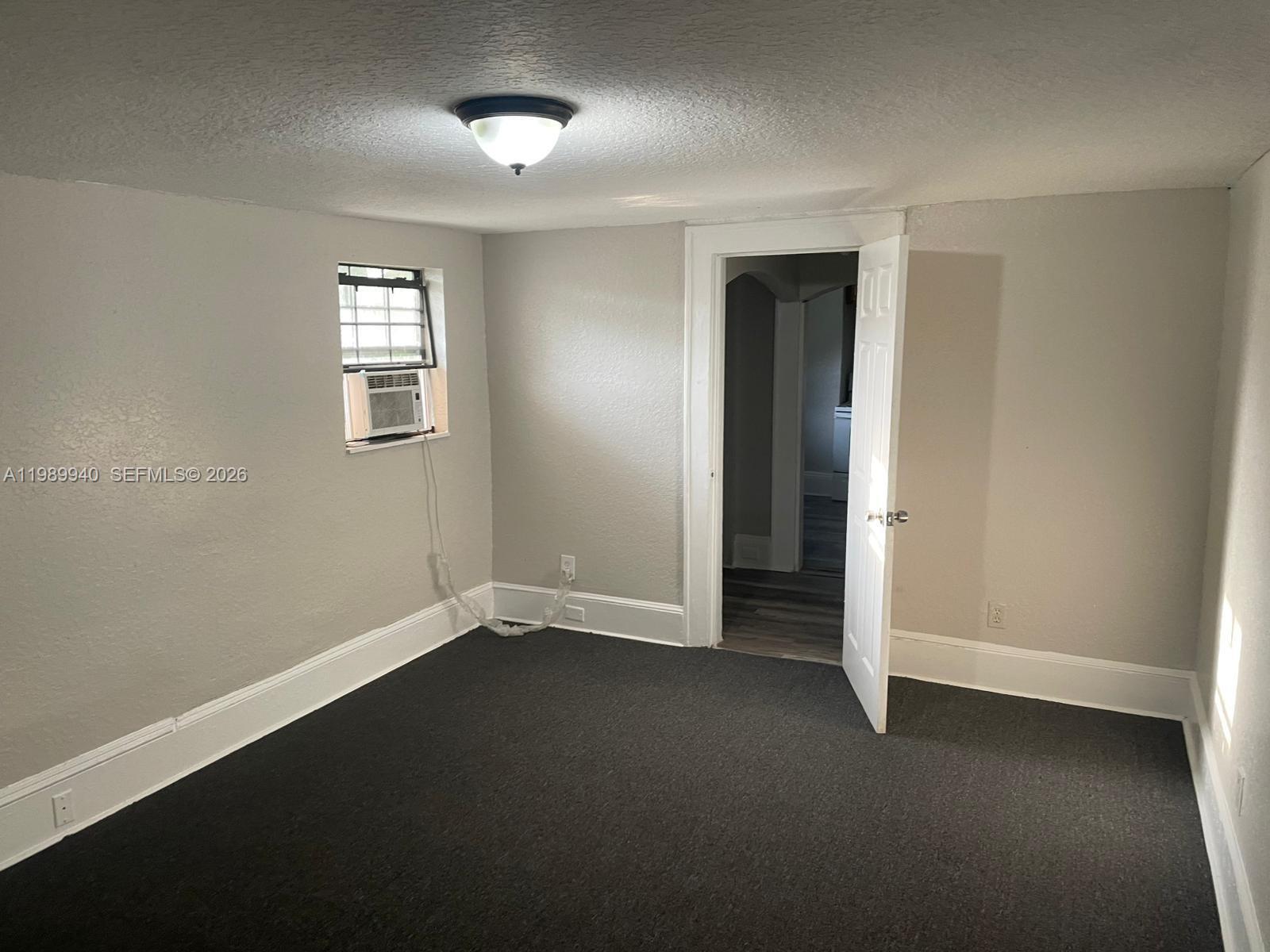 A bedroom with gray walls, dark carpeting, a window air conditioner, and an open doorway — 1129 Grothe St, Jacksonville FL 32209, JACKSONVILLE, FL