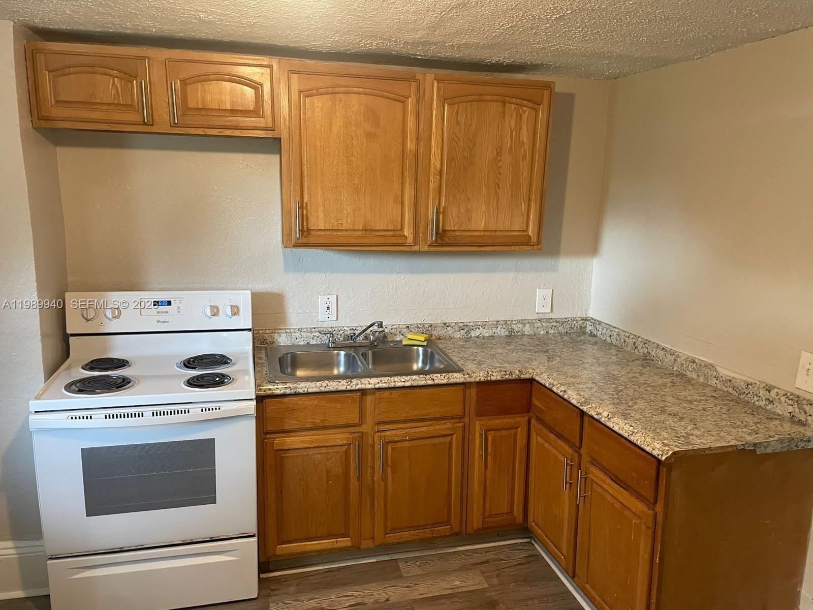 A kitchen features wood cabinets, a white electric stove, and a speckled laminate countertop — 1129 Grothe St, Jacksonville FL 32209, JACKSONVILLE, FL