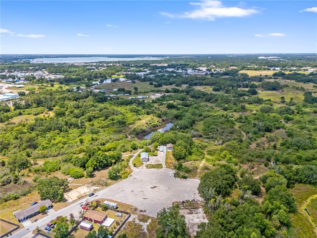 An aerial view shows a large paved lot with two small buildings surrounded by trees — 1100 SKYVIEW BOULEVARD UNIT 1, LAKELAND, FL