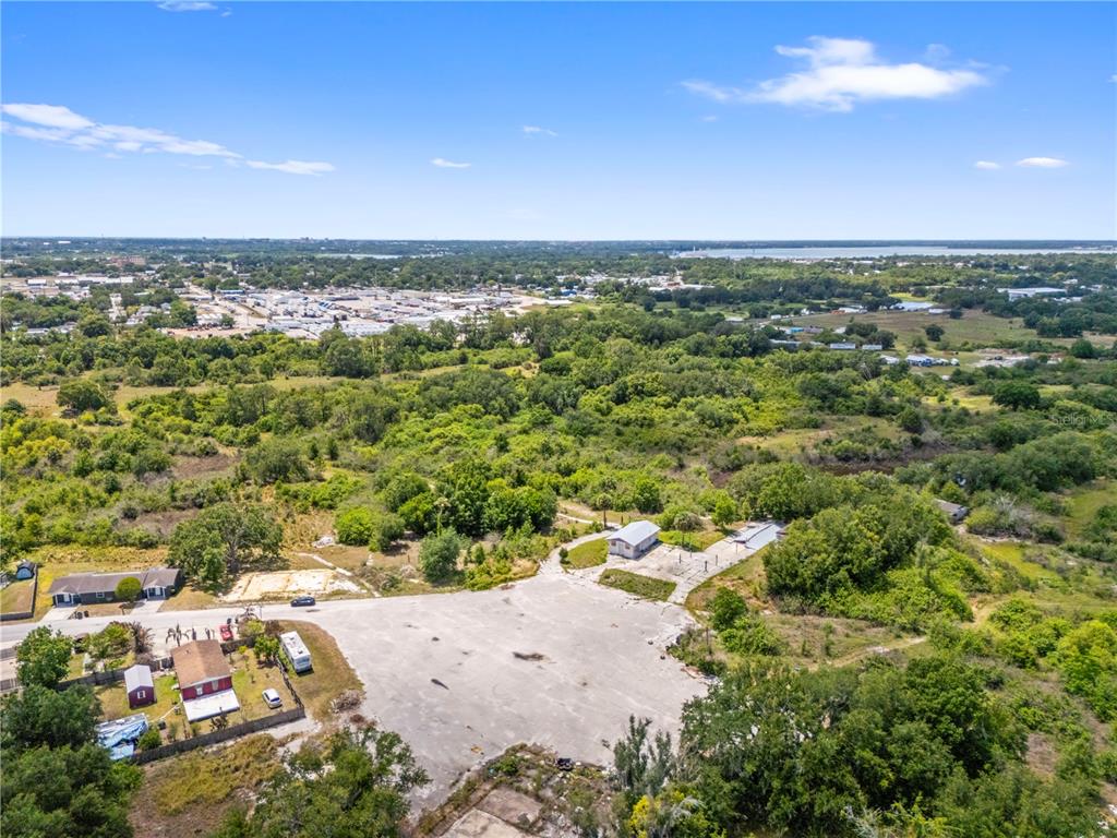 An aerial view shows a large paved lot with a small building and surrounding trees — 1100 SKYVIEW BOULEVARD UNIT 1, LAKELAND, FL