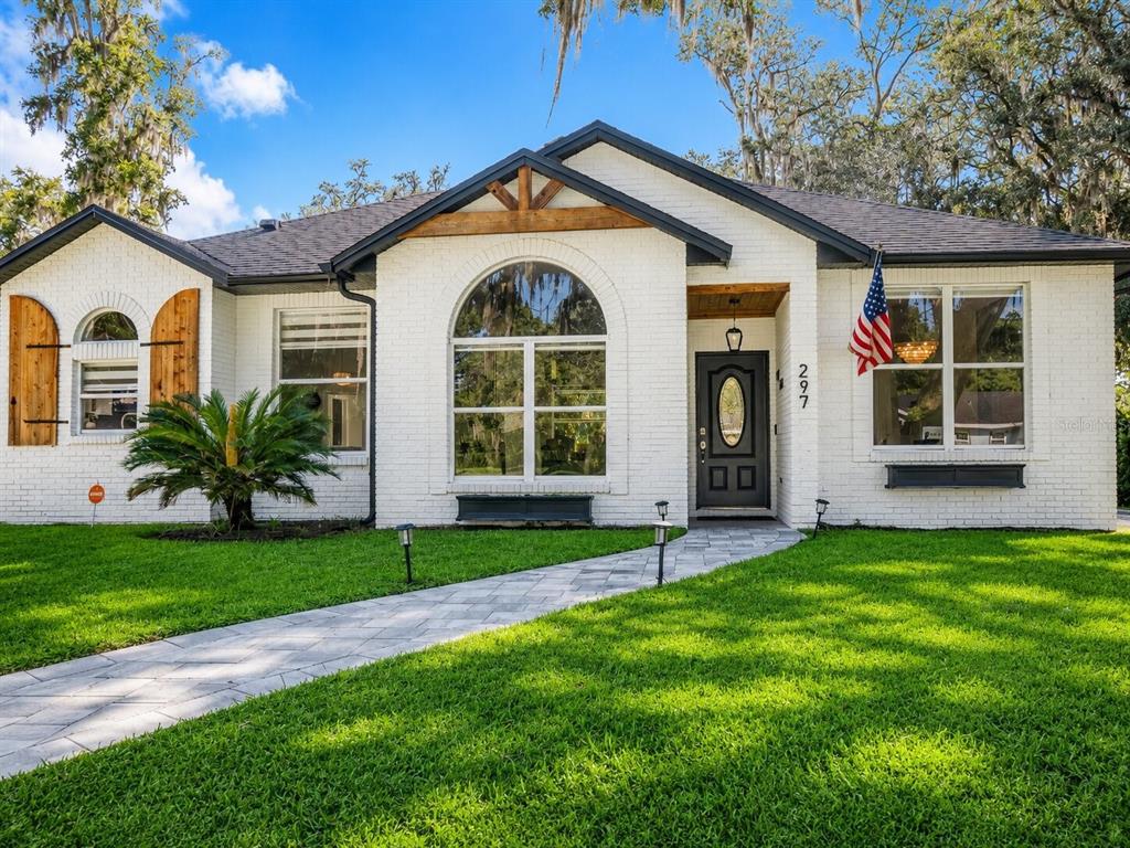 A white brick house with a dark roof, arched window, and a paved walkway — 297 N LAKE JESSUP AVENUE, OVIEDO, FL