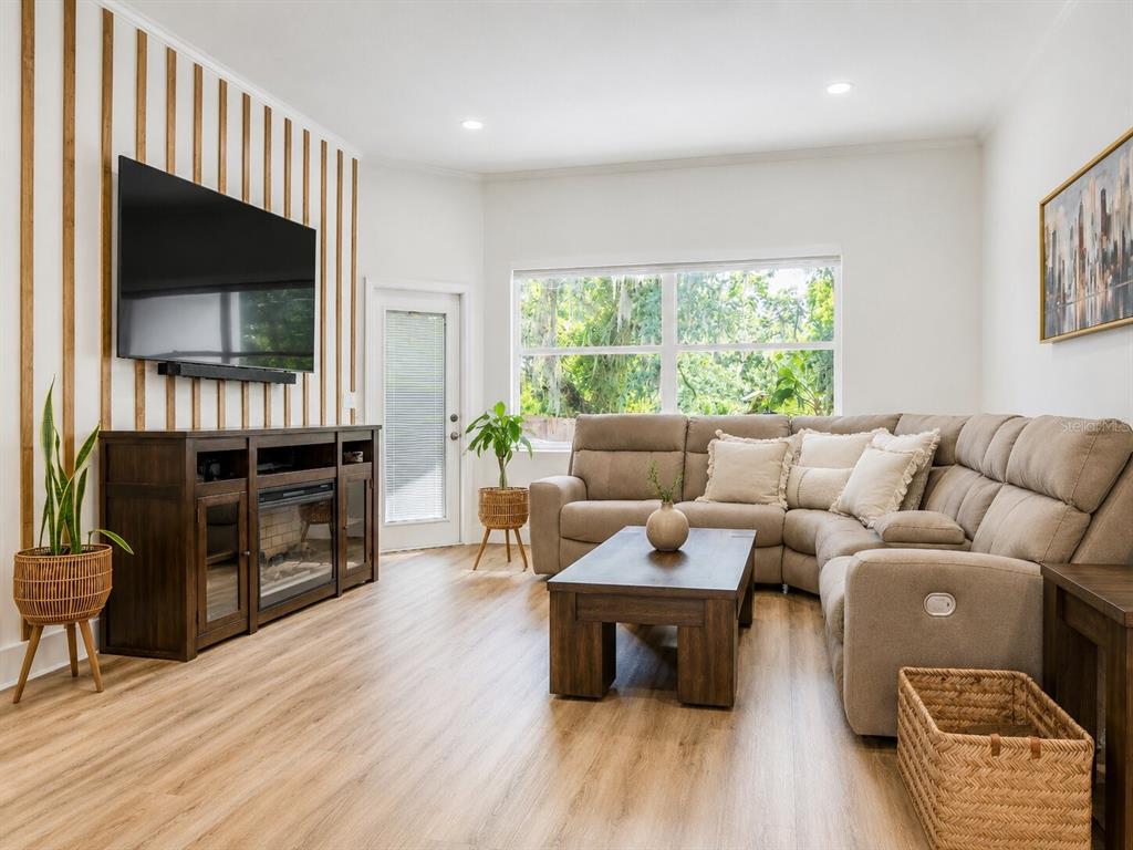 A living room features a wood-slat accent wall, a sectional sofa, and light wood flooring — 297 N LAKE JESSUP AVENUE, OVIEDO, FL
