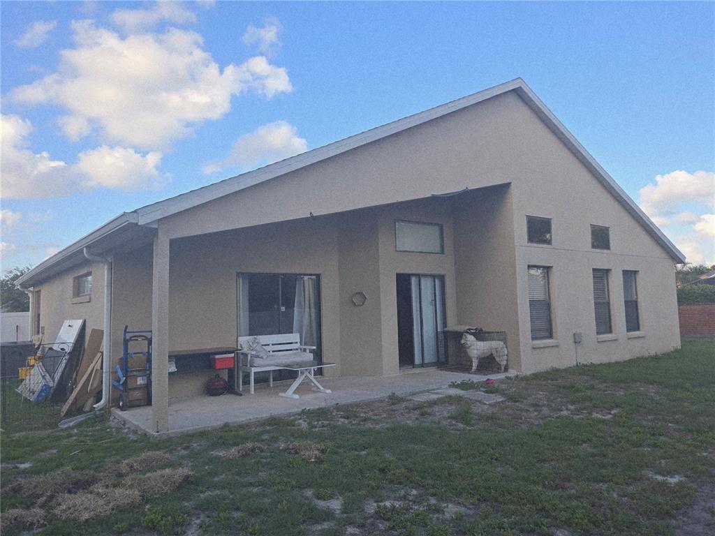 The rear exterior of a beige house features a covered patio and a fenced dog — 1651 RIVER BIRCH AVENUE, OVIEDO, FL