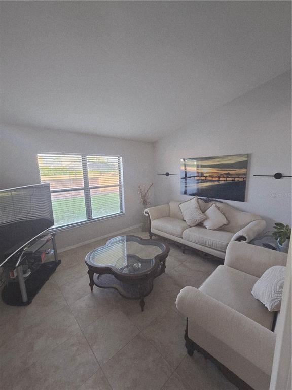 A living room features light-colored sofas, a glass-topped coffee table, and tile flooring — 1651 RIVER BIRCH AVENUE, OVIEDO, FL