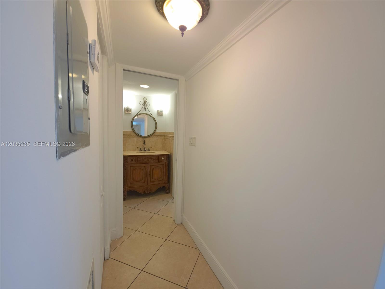 A hallway leads to a bathroom featuring a wooden vanity and a circular mirror — 401 Ocean Dr # 304, Miami Beach FL 33139, MIAMI BEACH, FL