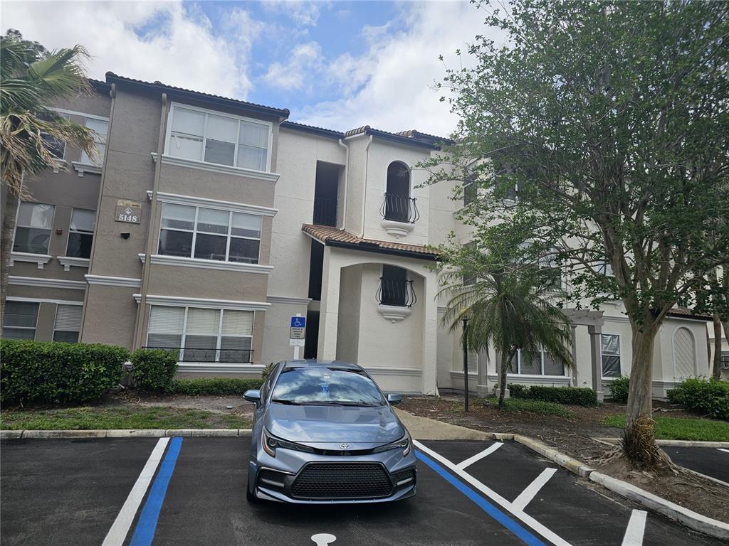 A light-colored multi-story apartment building features a blue car parked in a handicap space — 5132 CONROY ROAD UNIT 937, ORLANDO, FL