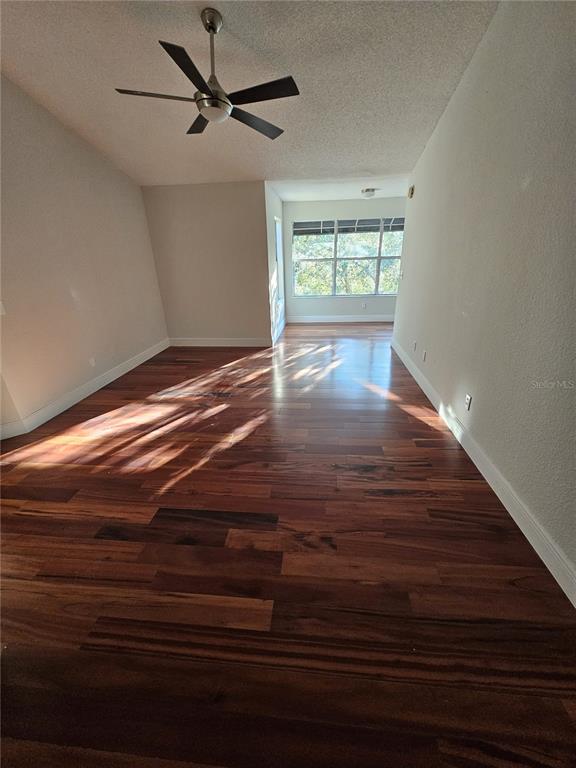 An empty room features dark wood flooring, white walls, and a ceiling fan — 5132 CONROY ROAD UNIT 937, ORLANDO, FL