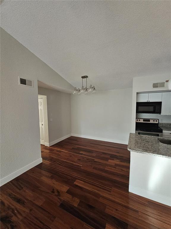 A dining area with dark wood floors, a modern chandelier, and an adjacent kitchen — 5132 CONROY ROAD UNIT 937, ORLANDO, FL