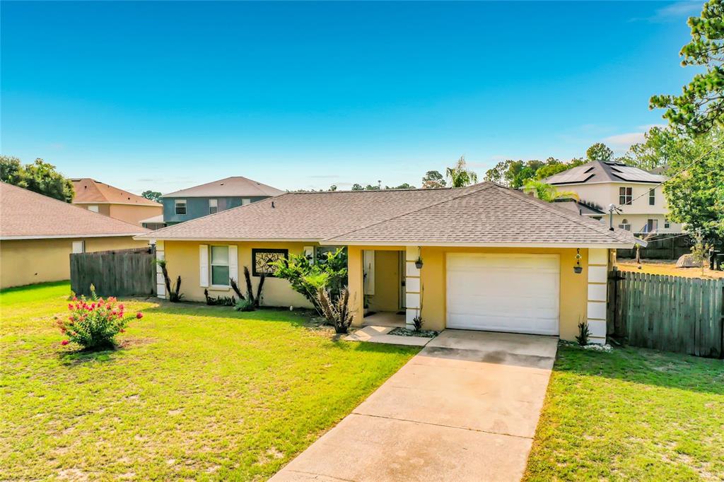 A single-story yellow house with a white garage door and a concrete driveway — 13 BAHIA PASS RUN, OCALA, FL