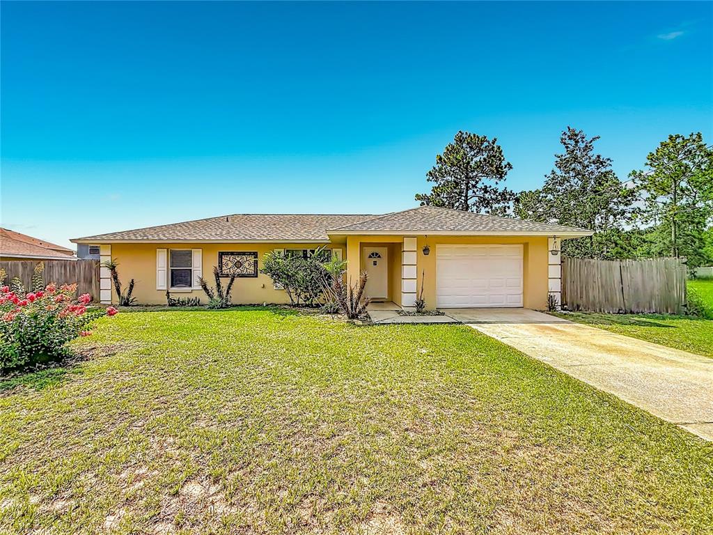 A single-story yellow house with a white garage door and a front lawn — 13 BAHIA PASS RUN, OCALA, FL