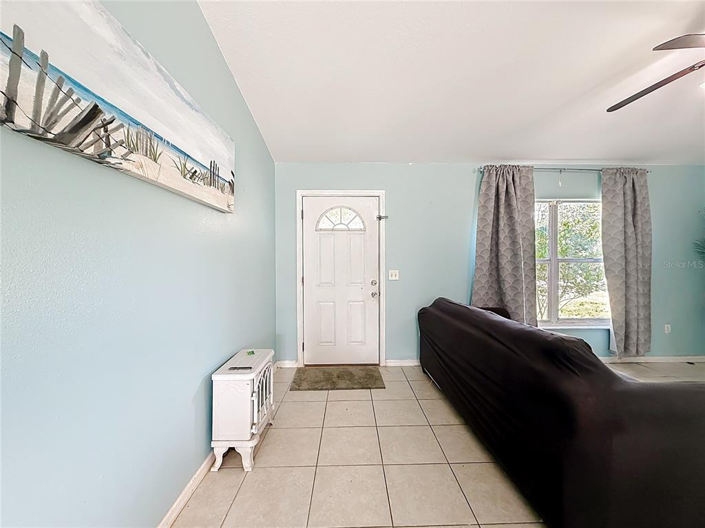 A living room features light blue walls, tile flooring, a white front door, and a sofa — 13 BAHIA PASS RUN, OCALA, FL