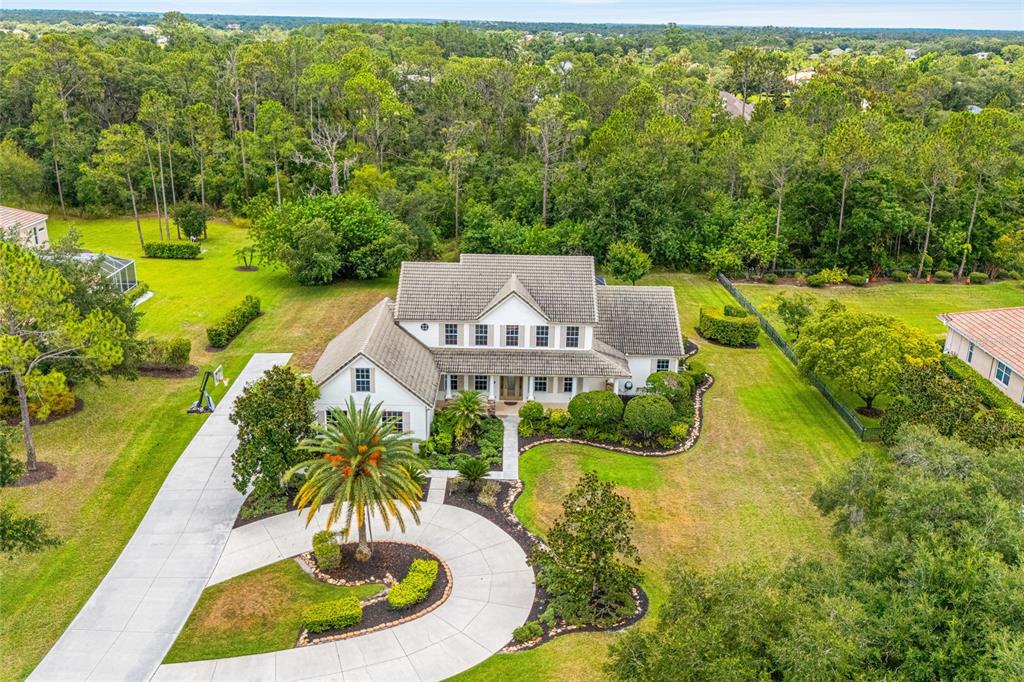 An aerial view shows a two-story white house with a circular driveway and landscaping — 22304 DEER POINTE CROSSING, BRADENTON, FL