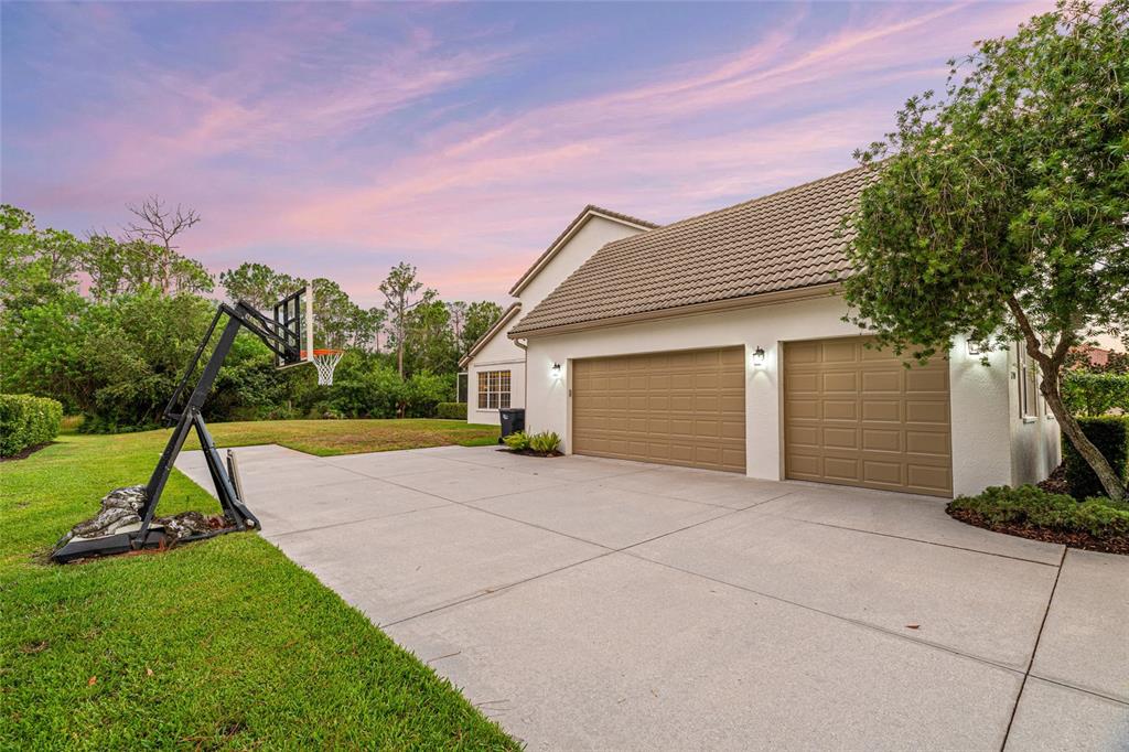 A two-car garage with tan doors and a basketball hoop on a concrete driveway — 22304 DEER POINTE CROSSING, BRADENTON, FL