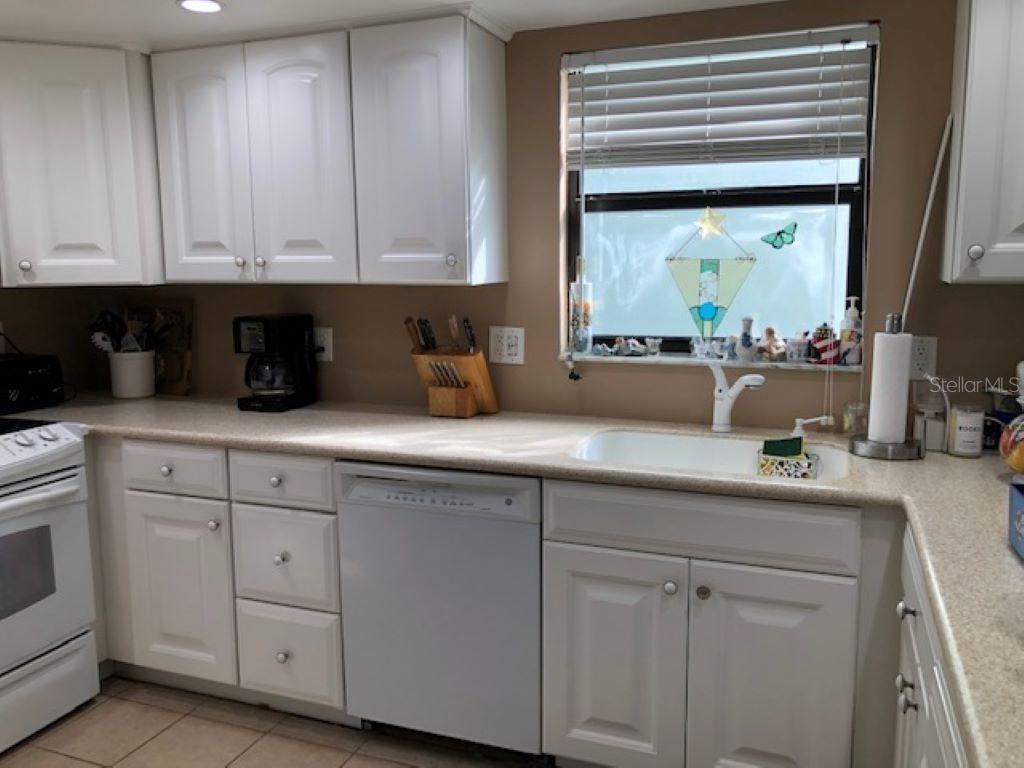 A kitchen features white cabinets, a light-colored countertop, a white dishwasher, and a window — 1571 S ATLANTIC AVENUE UNIT 205, NEW SMYRNA BEACH, FL
