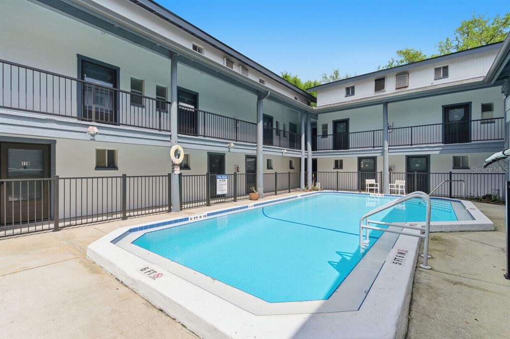 A swimming pool sits in the center of a two-story apartment building courtyard — 1100 TURNER STREET, CLEARWATER, FL