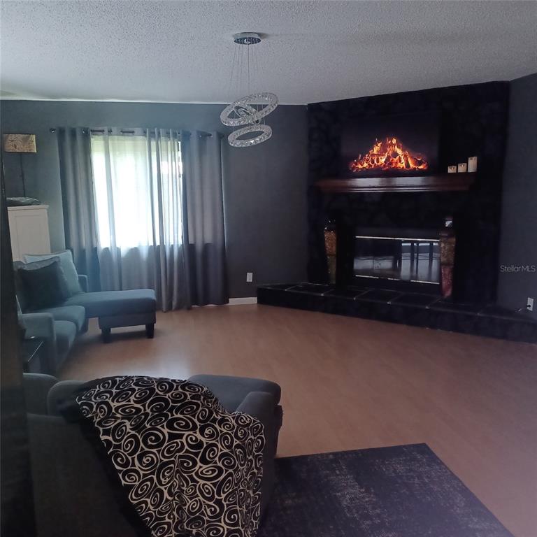 A living room features a dark stone fireplace, light wood flooring, and a modern chandelier — 31 FREELAND LANE, PALM COAST, FL