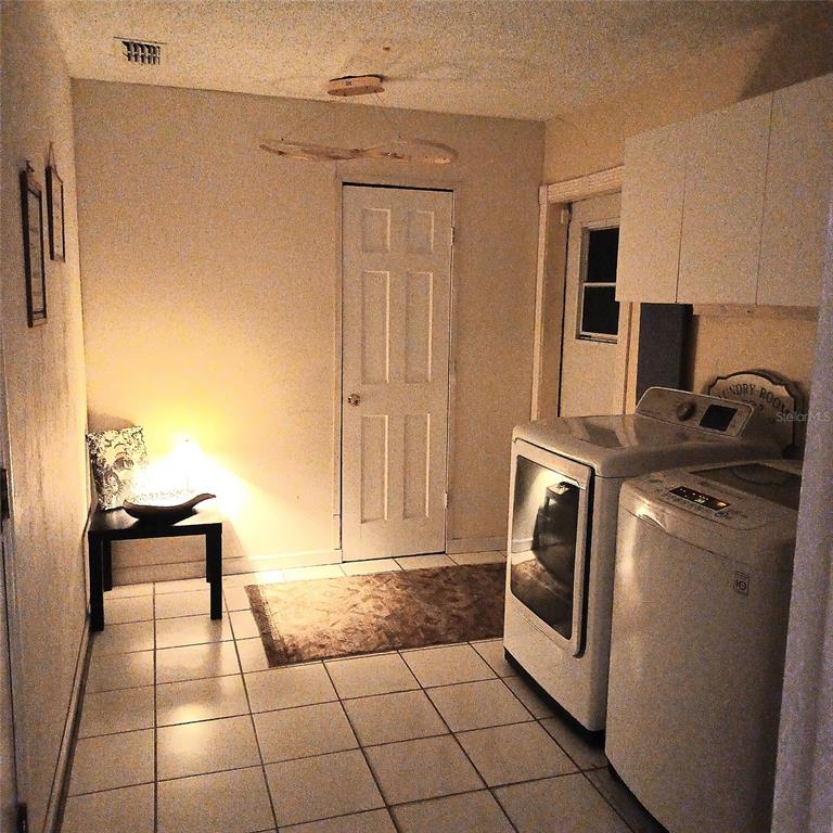 A laundry room with white tile floors, a washer and dryer, and a white door — 31 FREELAND LANE, PALM COAST, FL