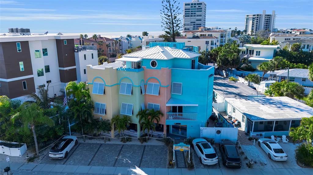 An aerial view shows a colorful, multi-story building with a parking lot in front — 5322 CALLE DE LA SIESTA, SARASOTA, FL