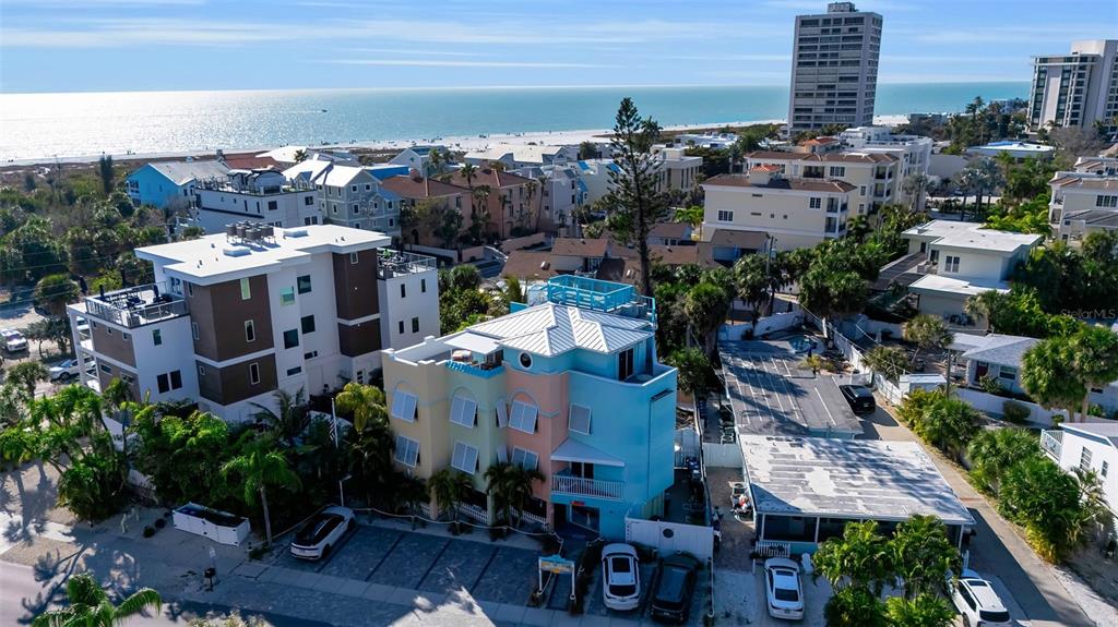 An aerial view shows a multi-story pastel building near the beach and ocean — 5322 CALLE DE LA SIESTA, SARASOTA, FL