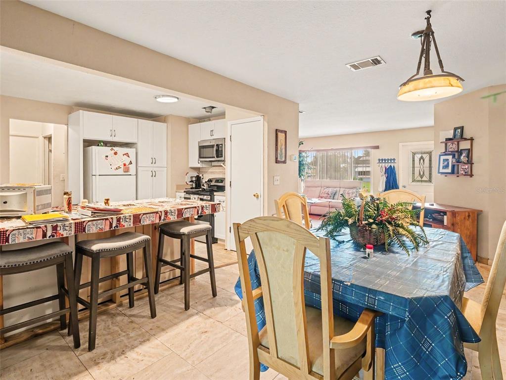 A kitchen with a breakfast bar and dining area featuring tile floors and light-colored cabinets — 6716 DENNISON AVENUE, NORTH PORT, FL