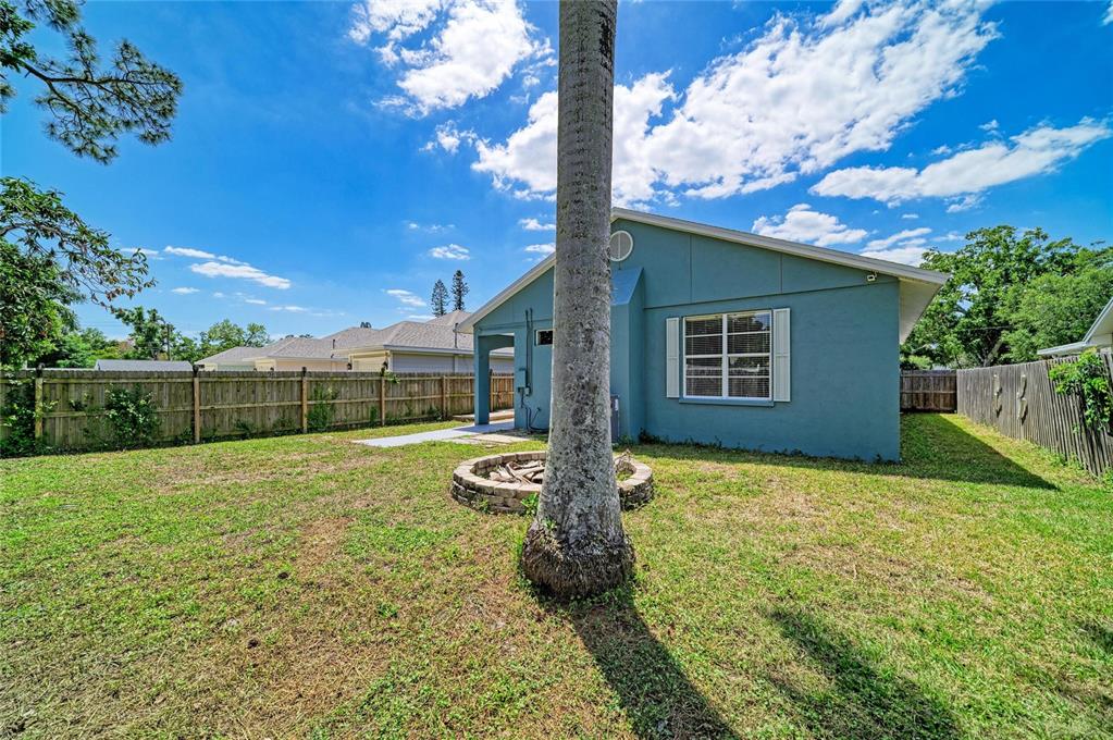 A backyard view of a blue house with a fire pit and a palm tree — 1609 17TH STREET W, BRADENTON, FL