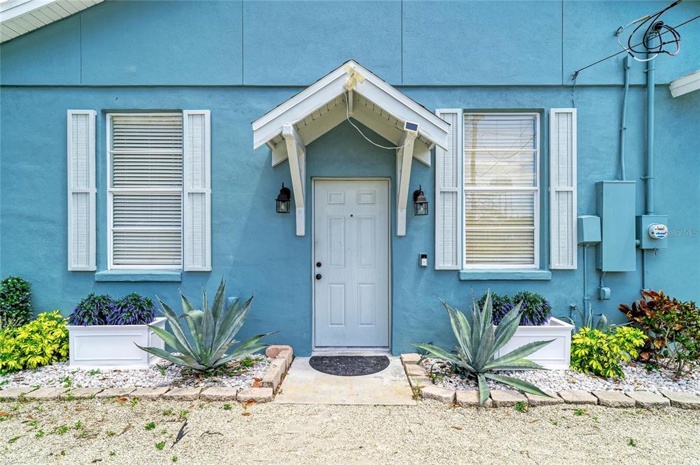 A light blue exterior wall features a central white door under a small gable roof — 1609 17TH STREET W, BRADENTON, FL