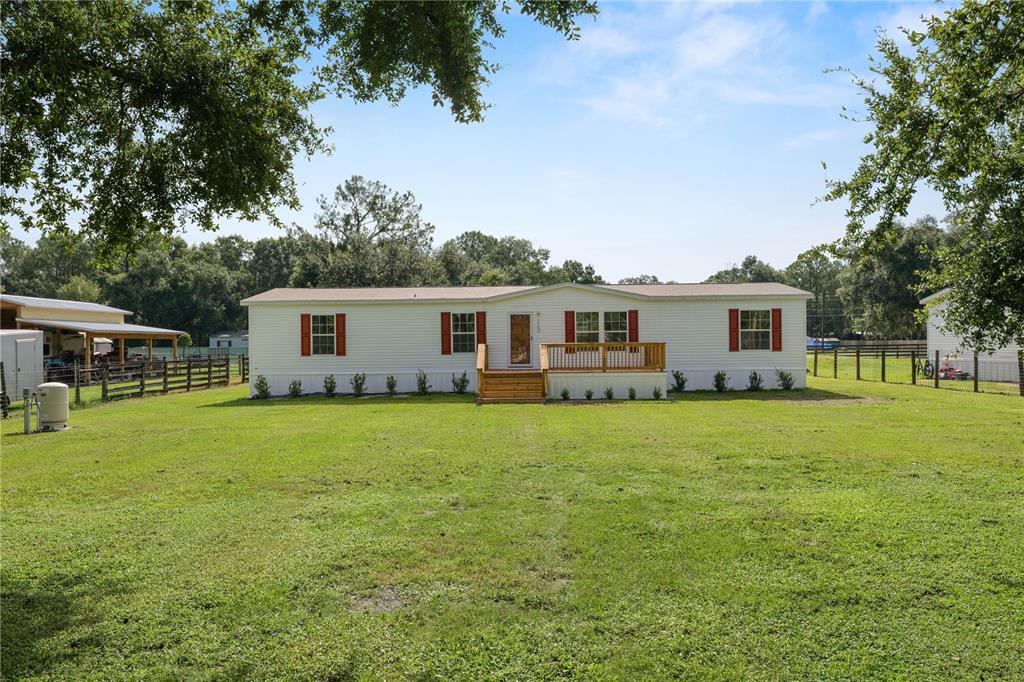 A single-story manufactured home with white siding and red shutters sits on a grassy lot — 7103 GLEN MEADOW DRIVE, LAKELAND, FL