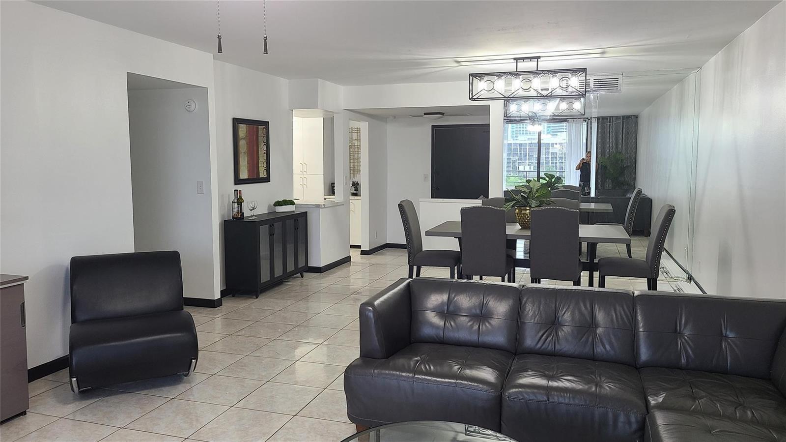 A living and dining area with tile floors, dark furniture, and a modern light fixture — 2500 Parkview Drive # 802, Hallandale Beach FL 33009, HALLANDALE BEACH, FL