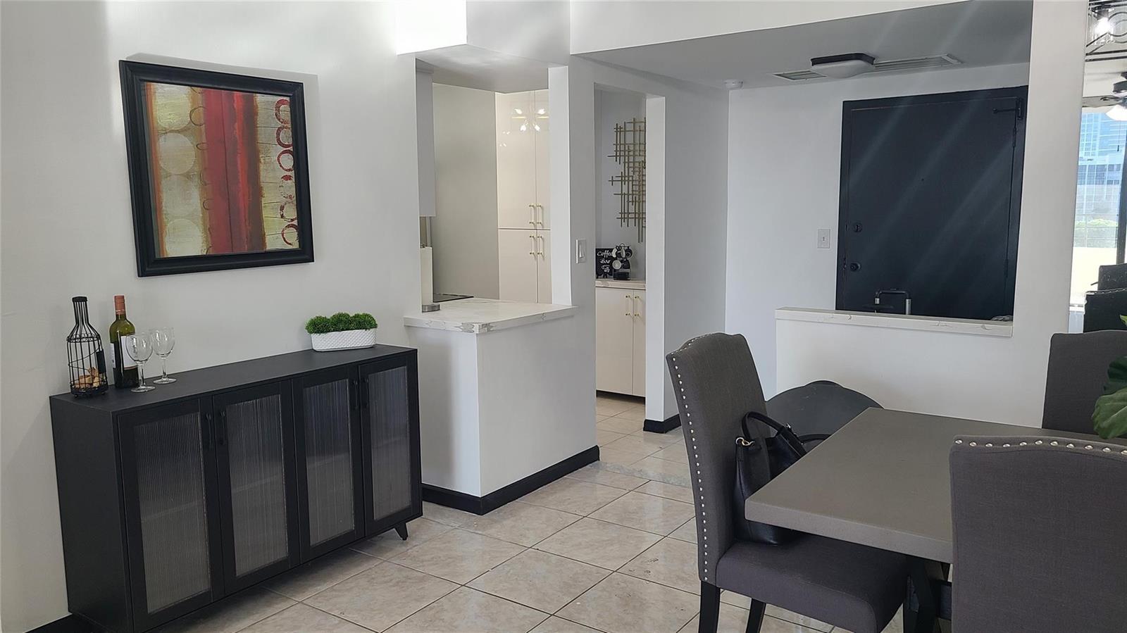 A dining area features a dark sideboard, a gray table with chairs, and tiled flooring — 2500 Parkview Drive # 802, Hallandale Beach FL 33009, HALLANDALE BEACH, FL
