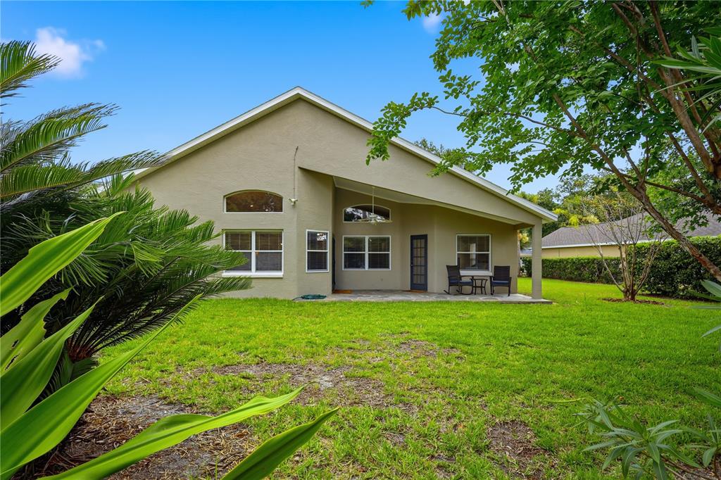 The rear exterior of a tan house features a covered patio and a grassy yard — 42 SHINNECOCK DRIVE, PALM COAST, FL