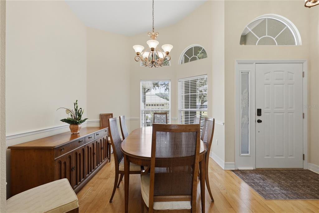 A dining room features a wooden table, chairs, a sideboard, and a white front door — 42 SHINNECOCK DRIVE, PALM COAST, FL