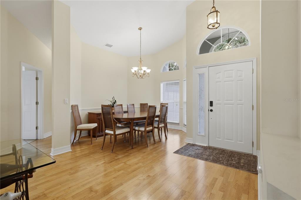 A dining room with hardwood floors, a chandelier, and an entryway with a front door — 42 SHINNECOCK DRIVE, PALM COAST, FL