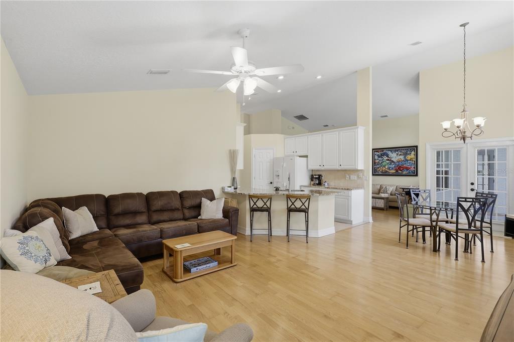 An open-concept living room and kitchen featuring hardwood floors, a sectional sofa, and white cabinetry — 42 SHINNECOCK DRIVE, PALM COAST, FL